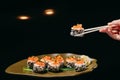 Tartaro Roll in Chinese chopsticks in hand over the dish on the table Royalty Free Stock Photo
