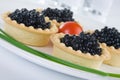 Tartlet with black caviar on a white platter