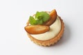 Tartlet filled with vanilla custard plum slices on top on white background