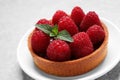 Tartlet with fresh raspberries and mint on light grey table. Delicious dessert