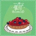 Tartlet with red and blue berries on lacy napkin