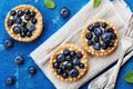 Tartlets with blueberries, bilberry, ricotta and honey syrup on vintage background top view. Delicious dessert. Flat lay styling.