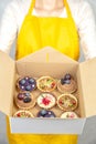 Tartlets in box in hand of woman in apron