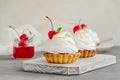 Tartlets with cherry filling and Italian meringue with a cocktail cherry on top on a board on a concrete background. Royalty Free Stock Photo