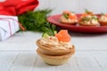 Tartlets with cream cheese and salted salm on a white wooden background. Tasty light snack for a party.