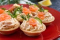 Tartlets with cream cheese and salted salmon on a red plate. Tasty light snack for a party. Finger Food.