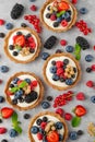 Tartlets with custard vanilla cream with fresh berries and mint on a gray concrete background. Summer dessert Royalty Free Stock Photo