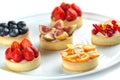 Tartlets with fruits and berries in a plate close-up on an isolated white background Royalty Free Stock Photo