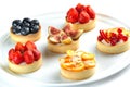 Tartlets with fruits and berries in a plate close-up on an isolated white background Royalty Free Stock Photo