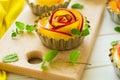 Tartlets with plum roses decorated mint leaves on white wooden background