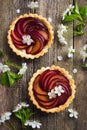 Tartlets with plum on wooden background