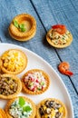 Tartlets with salads and shrimps on a white plate on wooden table