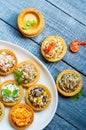 Tartlets with salads and shrimps on a white plate on wooden table