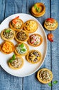 Tartlets with salads and shrimps on a white plate on wooden table