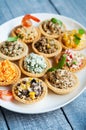 Tartlets with salads and shrimps on a white plate on wooden table