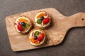 Tartlets with various berries on wooden cutting board