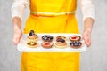 Tartlets on white plate in hand of woman in apron