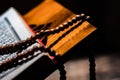 Tasbih or Islamic prayer beads on rustic wood plank, with Quran on rihal