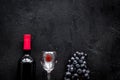 Taste red wine. Bottle of red wine, glass and black grape on black stone background top view copyspace Royalty Free Stock Photo