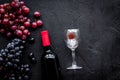 Taste red wine. Bottle of red wine, glass and black grape on black stone background top view copyspace Royalty Free Stock Photo