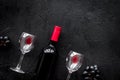 Taste red wine. Bottle of red wine, glass and black grape on black stone background top view copyspace Royalty Free Stock Photo