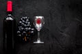 Taste red wine. Bottle of red wine, glass and black grape on black stone background top view copyspace Royalty Free Stock Photo