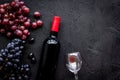 Taste red wine. Bottle of red wine, glass and black grape on black stone background top view copyspace Royalty Free Stock Photo