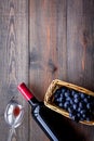 Taste red wine. Bottle of red wine, glass and black grape on dark wooden background top view copyspace Royalty Free Stock Photo
