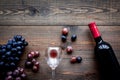 Taste red wine. Bottle of red wine, glass and black grape on dark wooden background top view copyspace Royalty Free Stock Photo