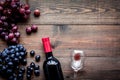 Taste red wine. Bottle of red wine, glass and black grape on dark wooden background top view copyspace Royalty Free Stock Photo