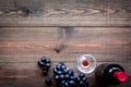 Taste red wine. Bottle of red wine, glass and black grape on dark wooden background top view copyspace Royalty Free Stock Photo