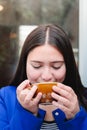 Taste of Serenity: Close-Up of a Latin Young Woman Enjoying a Scrumptious Coffee at the Outdoor Patio of a Cozy Cafe