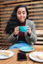 Taste of Serenity: Close-Up Shot of a Latina Woman Enjoying a Scrumptious Coffee at the Outdoor Patio of a Cozy Cafe