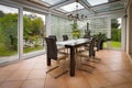 A tastefully furnished winter garden there is a dining table decorated with yellow tulips