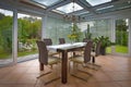 a tastefully furnished winter garden there is a dining table decorated with yellow tulips