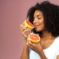 Tastes good and smells divine. Studio shot of an attractive young woman eating grapefruit against a pink background. Royalty Free Stock Photo