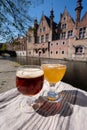 Tasting of Belgian beer on open cafe or bistro terrace with view on medieval houses and canals in Bruges, Belgium