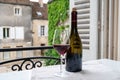 Tasting of burgundy red wine from grand cru pinot noir vineyards, glass and bottle of wine and view on old town street in