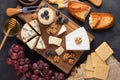 Tasting cheese dish on a dark stone plate. Food for wine and romantic date, cheese delicatessen on a black concrete background. To