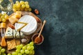 Tasting cheese dish on a wooden plate. Food for wine and romantic date  cheese delicatessen on a black concrete background. Top Royalty Free Stock Photo