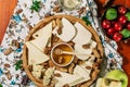 Tasting cheese dish with herbs and snacks on old light wooden table. Food for wine and romantic, cheese delicatessen. Menu design