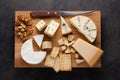 Tasting cheese dish on a wooden plate. Food for wine and romantic, cheese delicatessen on a dark stone table. Top view Royalty Free Stock Photo