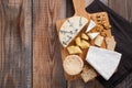 Tasting cheese dish on a wooden plate. Food for wine and romantic, cheese delicatessen on a wooden rustic table. Top view with cop Royalty Free Stock Photo