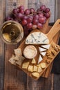 Tasting cheese dish on a wooden plate. Food for wine and romantic, cheese delicatessen on a wooden rustic table. Top view