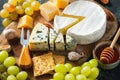 Tasting cheese dish on a wooden plate. Food for wine and romantic date  cheese delicatessen on a black concrete background Royalty Free Stock Photo