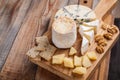 Tasting cheese dish on a wooden plate. Food for wine and romantic, cheese delicatessen on a wooden rustic table. Top view with cop Royalty Free Stock Photo