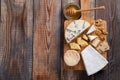 Tasting cheese dish on a wooden plate. Food for wine and romantic, cheese delicatessen on a wooden rustic table. Top view with cop
