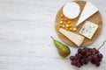 Tasting cheese with fruits on a white wooden background. Food for wine, top view. Flat lay, from above.