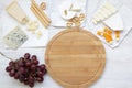 Tasting cheese with grapes, bread sticks, walnuts and pretzels on wooden background, top view. Food for romantic. Flat lay.