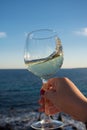 Tasting of glass of cold white wine on outdoor terrace with sea Royalty Free Stock Photo